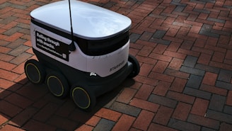 a white and black robot sitting on top of a brick road