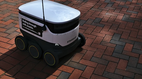a white and black robot sitting on top of a brick road