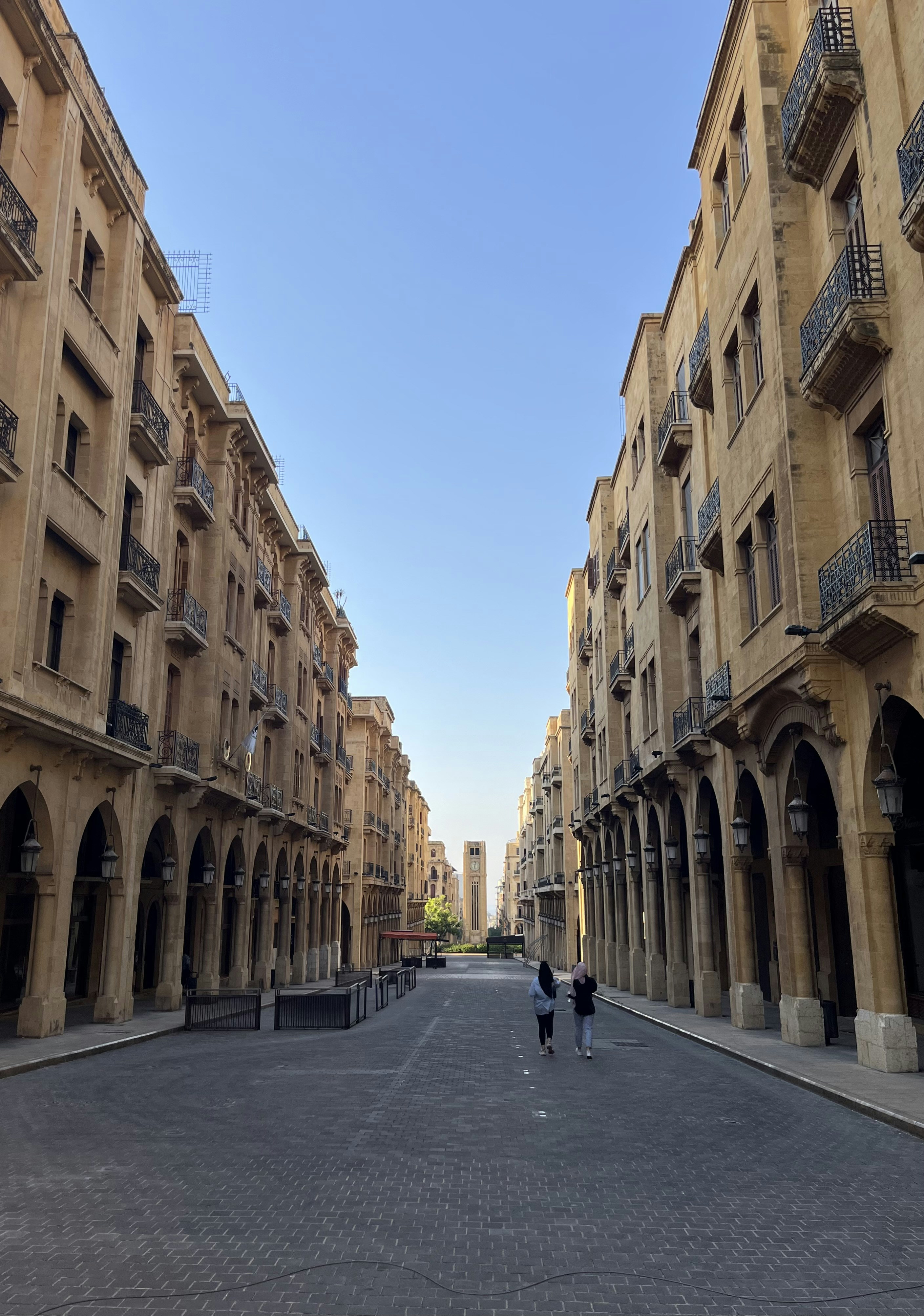 a couple of people walking down a street next to tall buildings