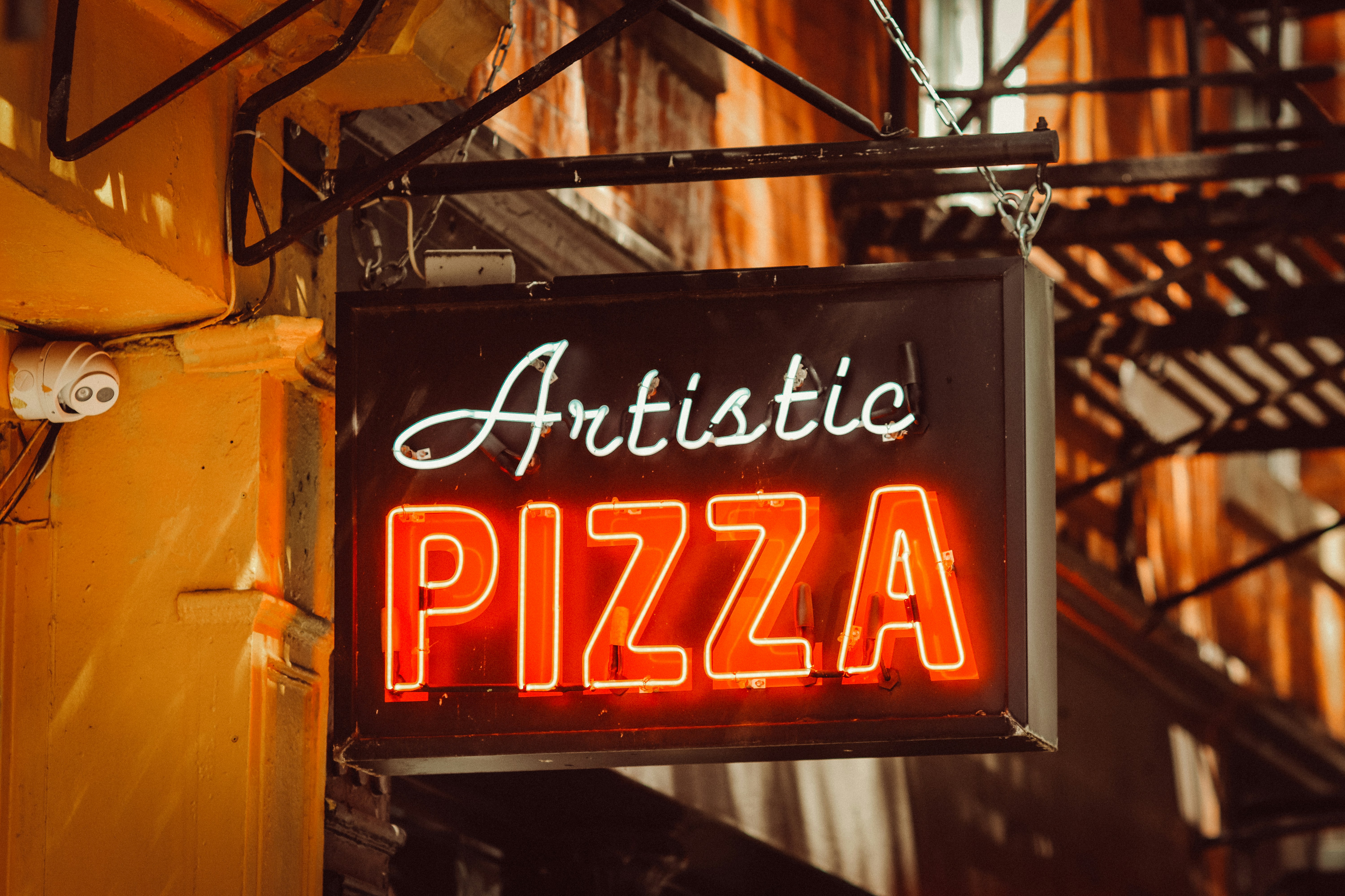 tanda neon yang bertuliskan pizza artistik tergantung di sisi gedung