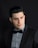 a man in a tuxedo poses for a picture