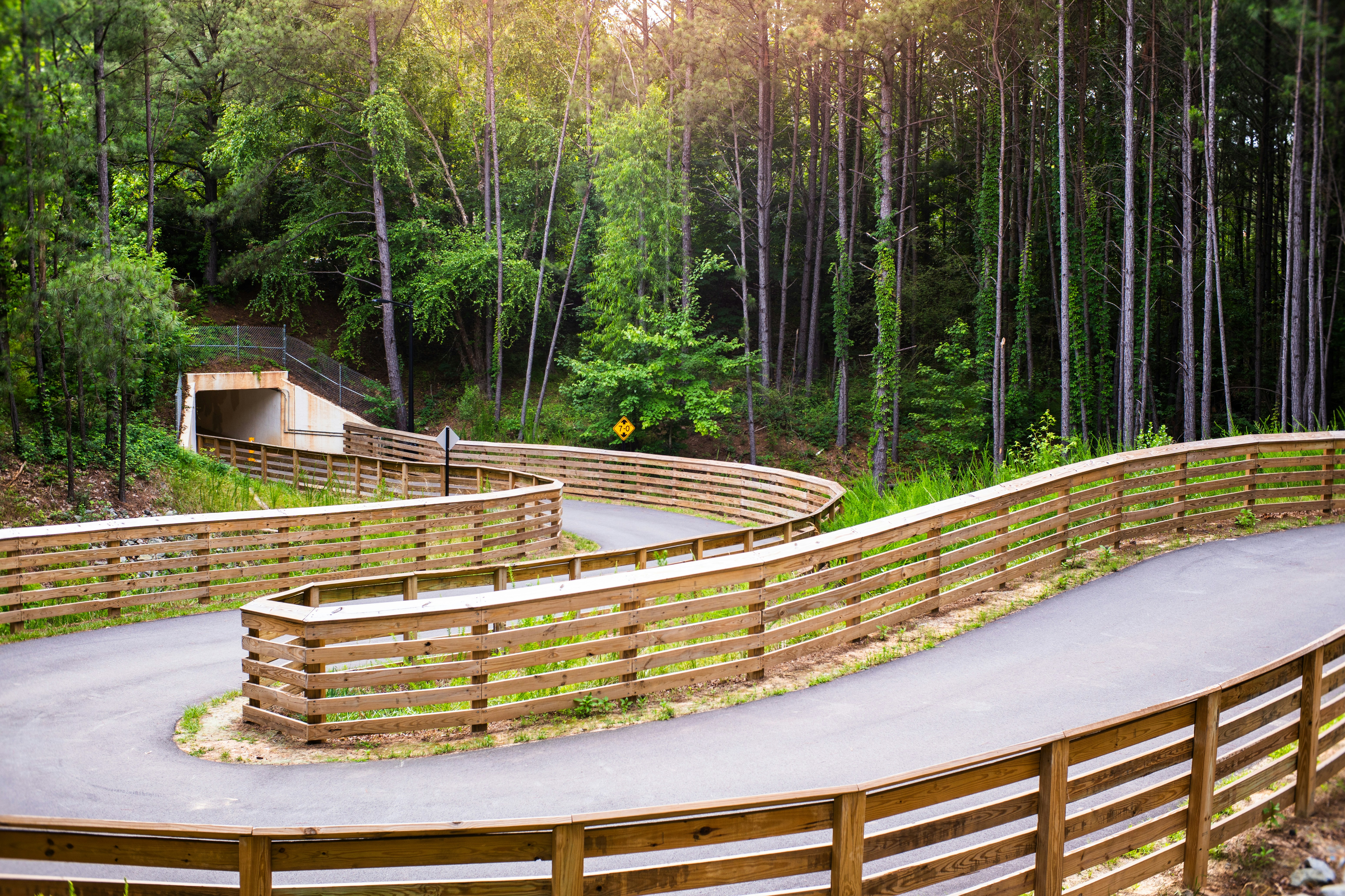 ein Holzzaun um eine geschwungene Straße im Wald