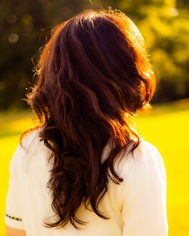 a woman with long hair standing in a field