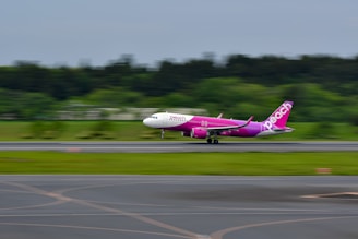 a pink and white plane is on a runway