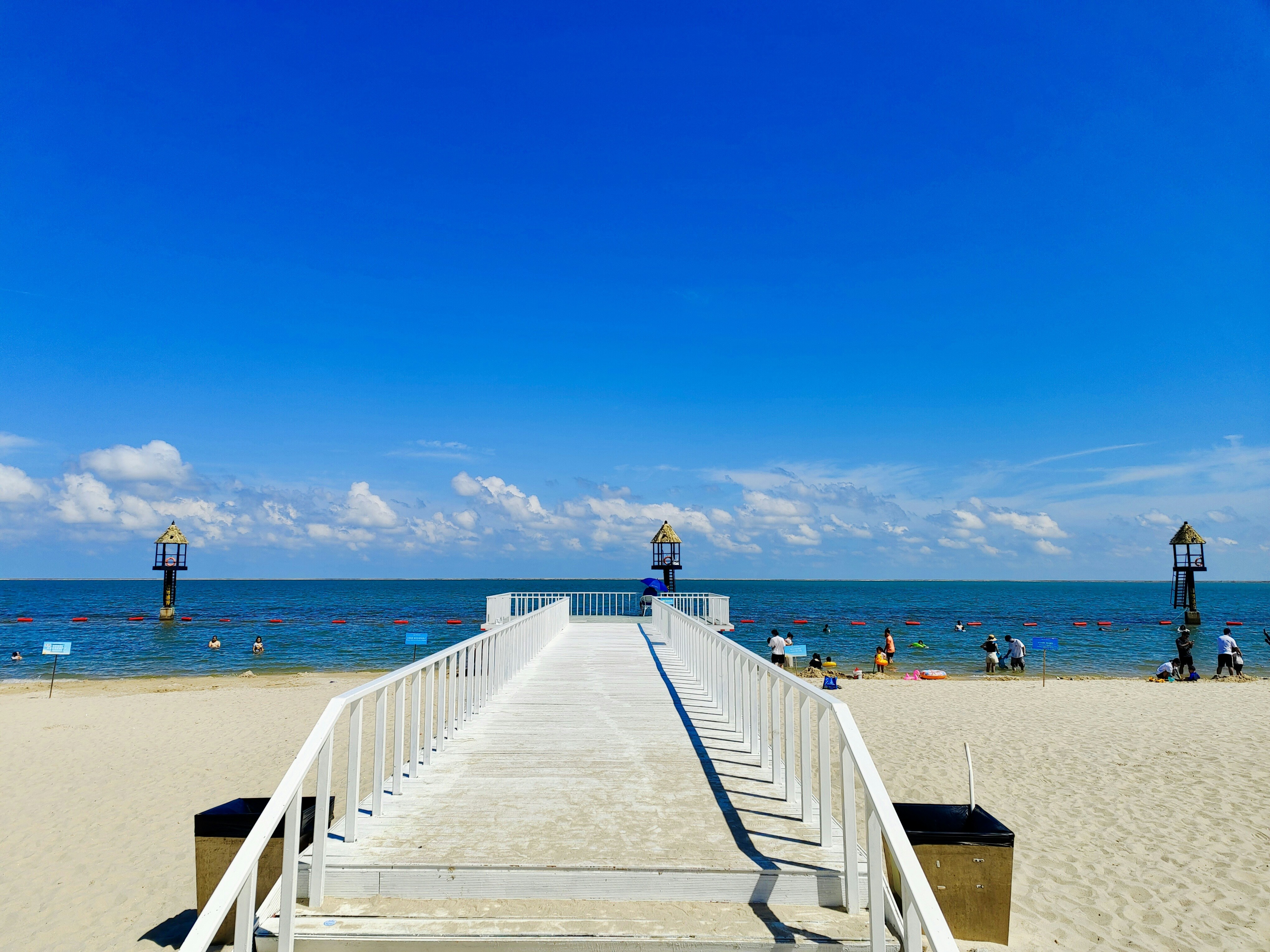 a beach with a white railing and people in the water