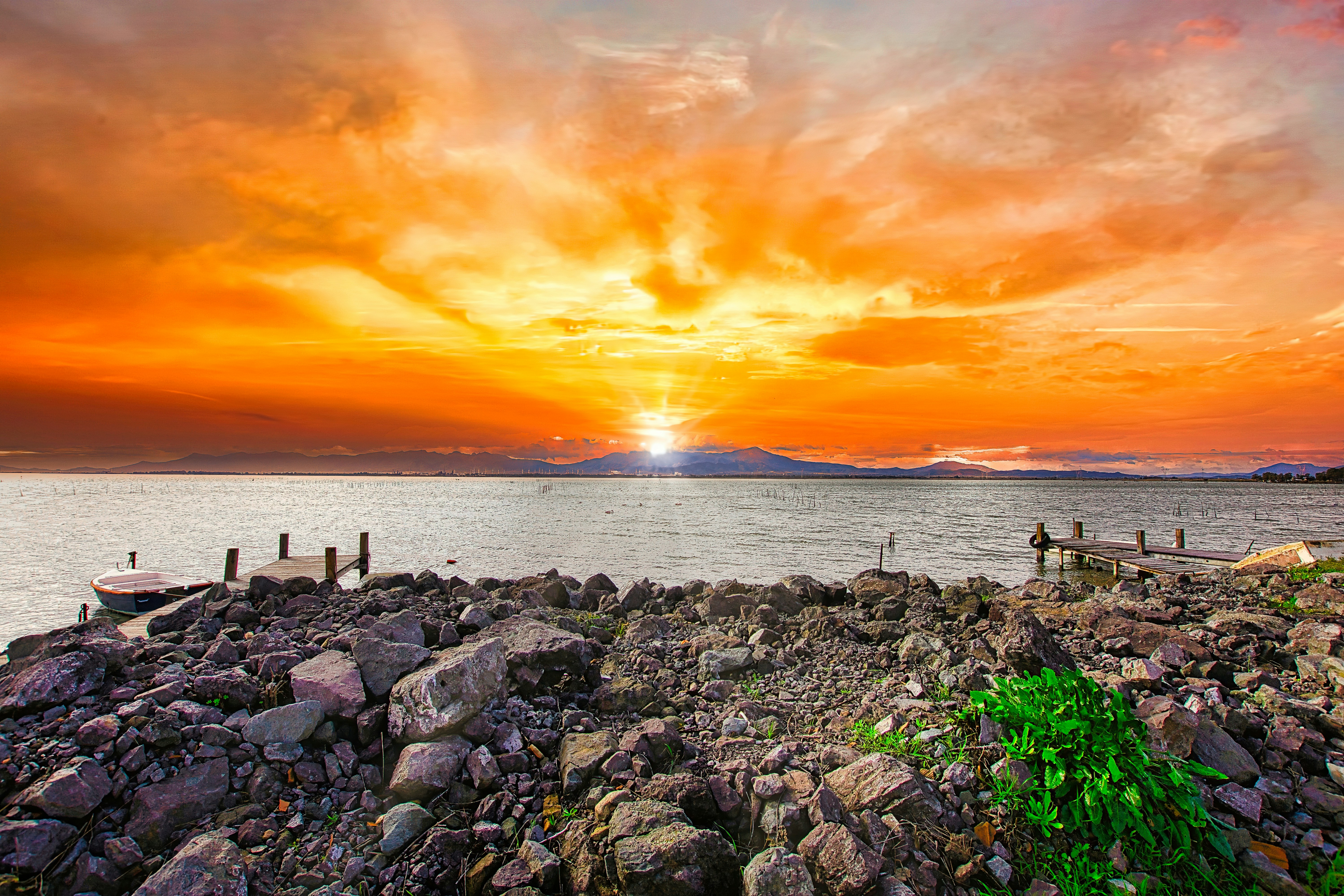 a sunset over a body of water with a boat in the distance