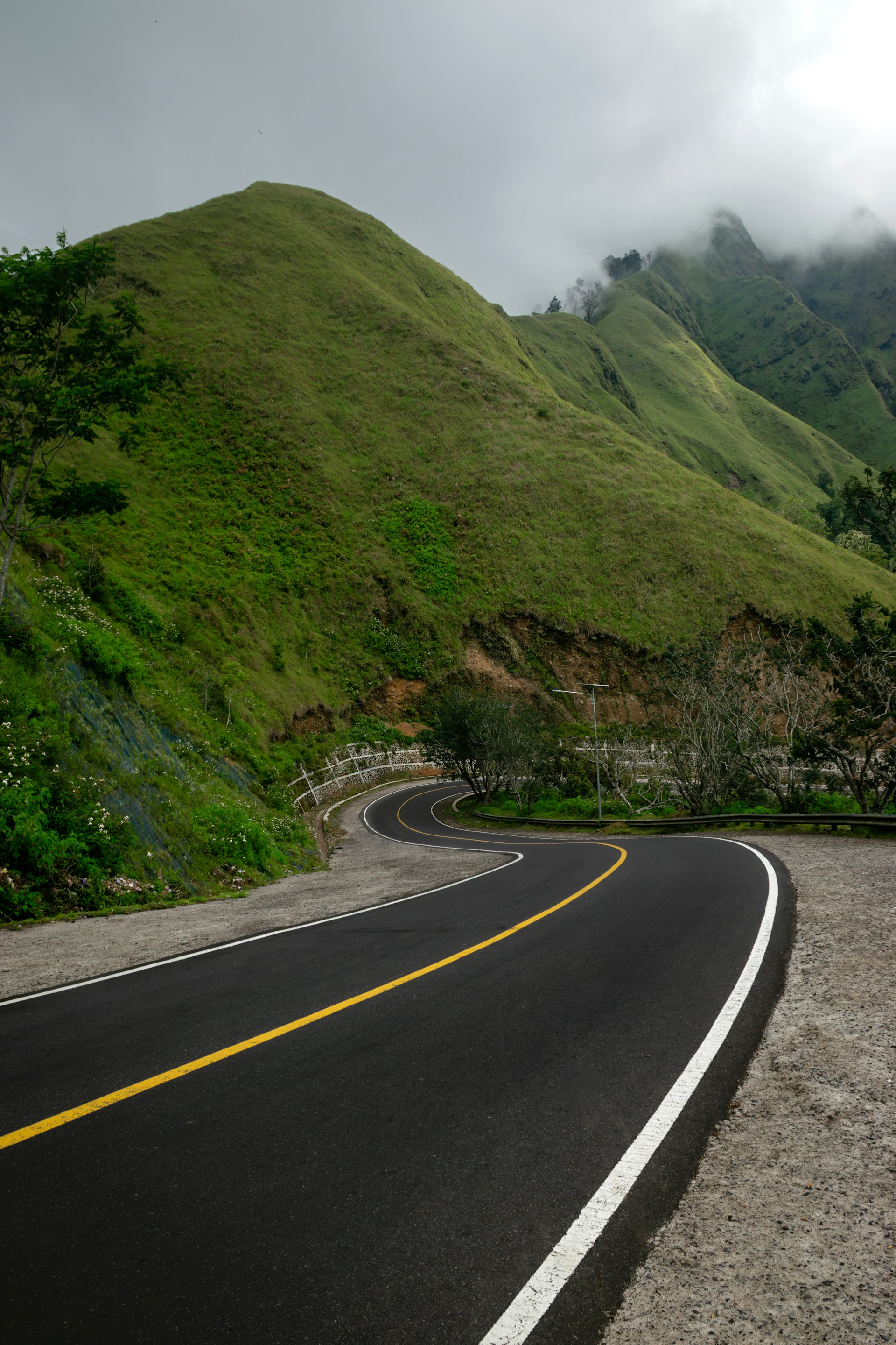 a curve in the road with a mountain in the background