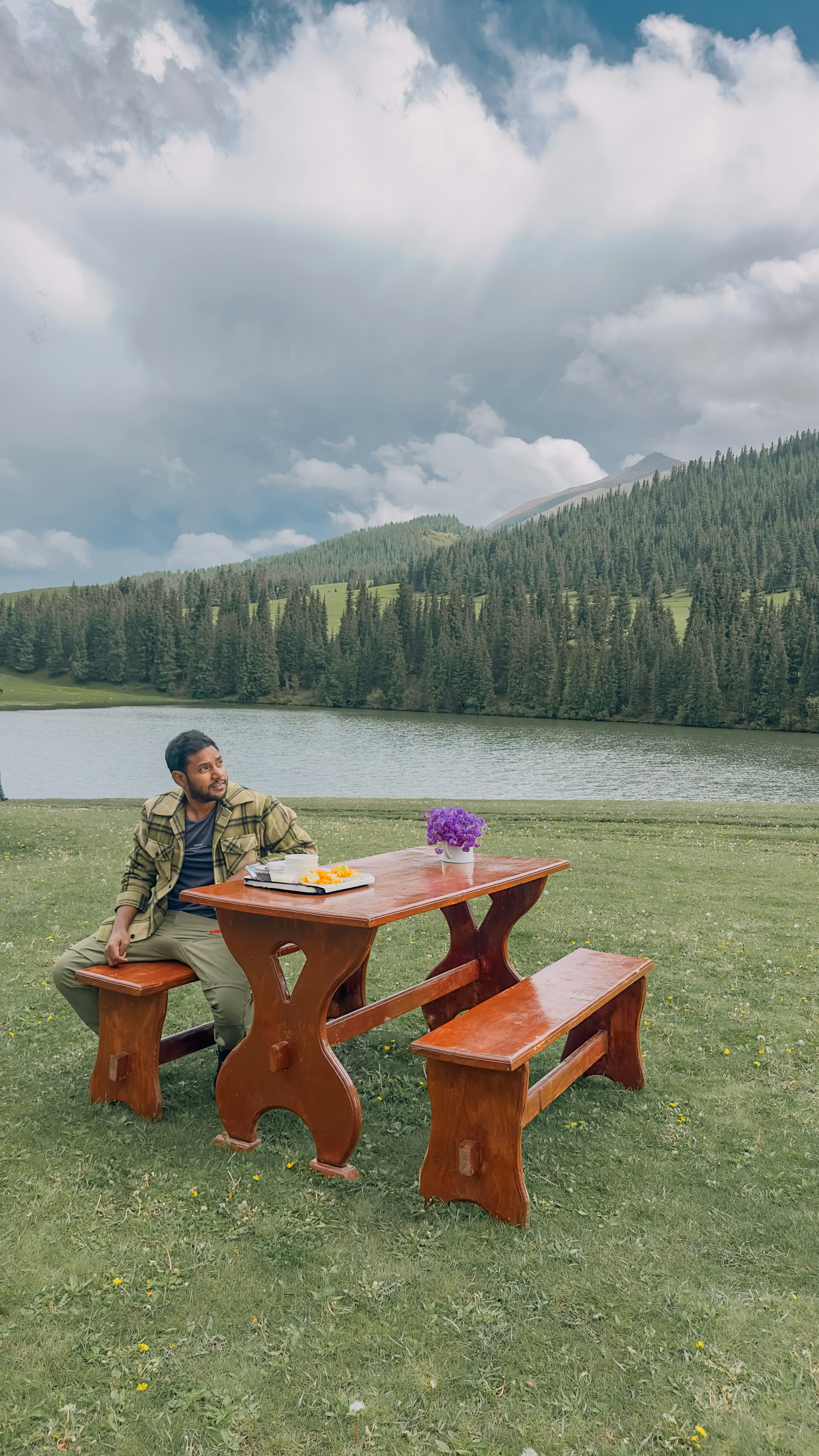 a man sitting at a picnic table in a field
