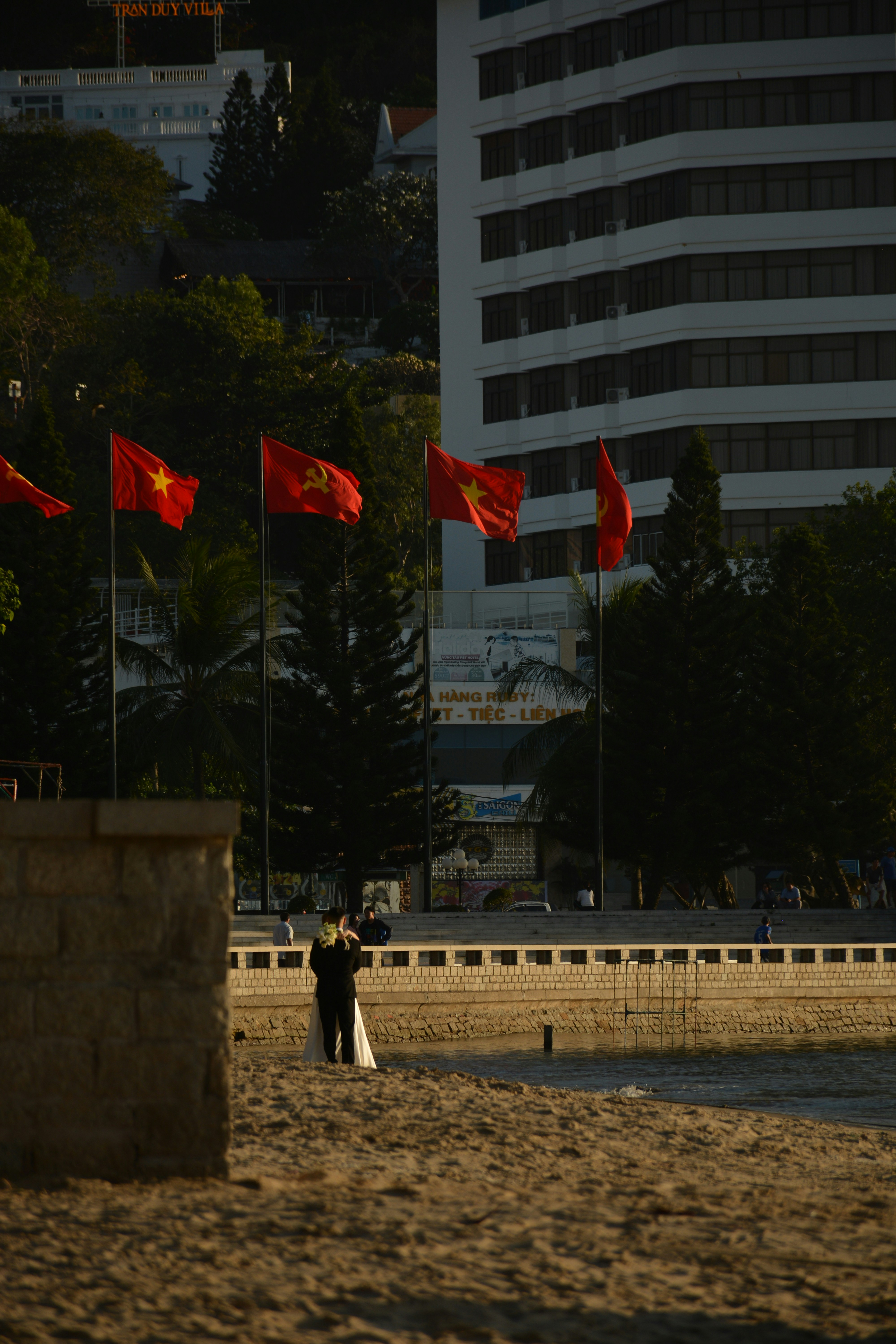 Quelques personnes debout au sommet d’une plage de sable