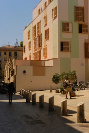 a man walking down a street next to a tall building