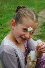 a little girl holding a stuffed animal and a flower