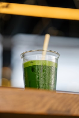a glass of green juice sitting on a table