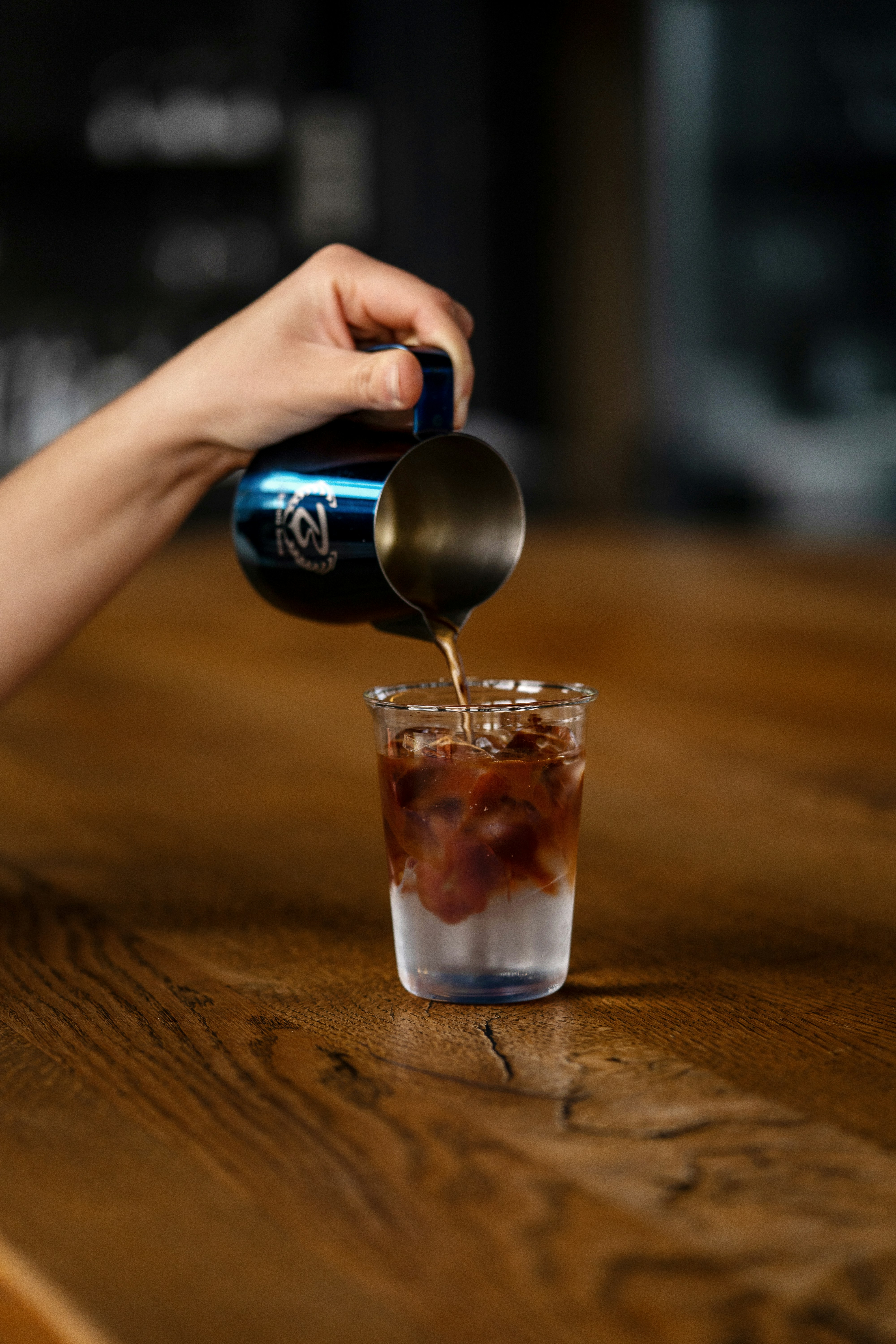 a person pouring a drink into a glass