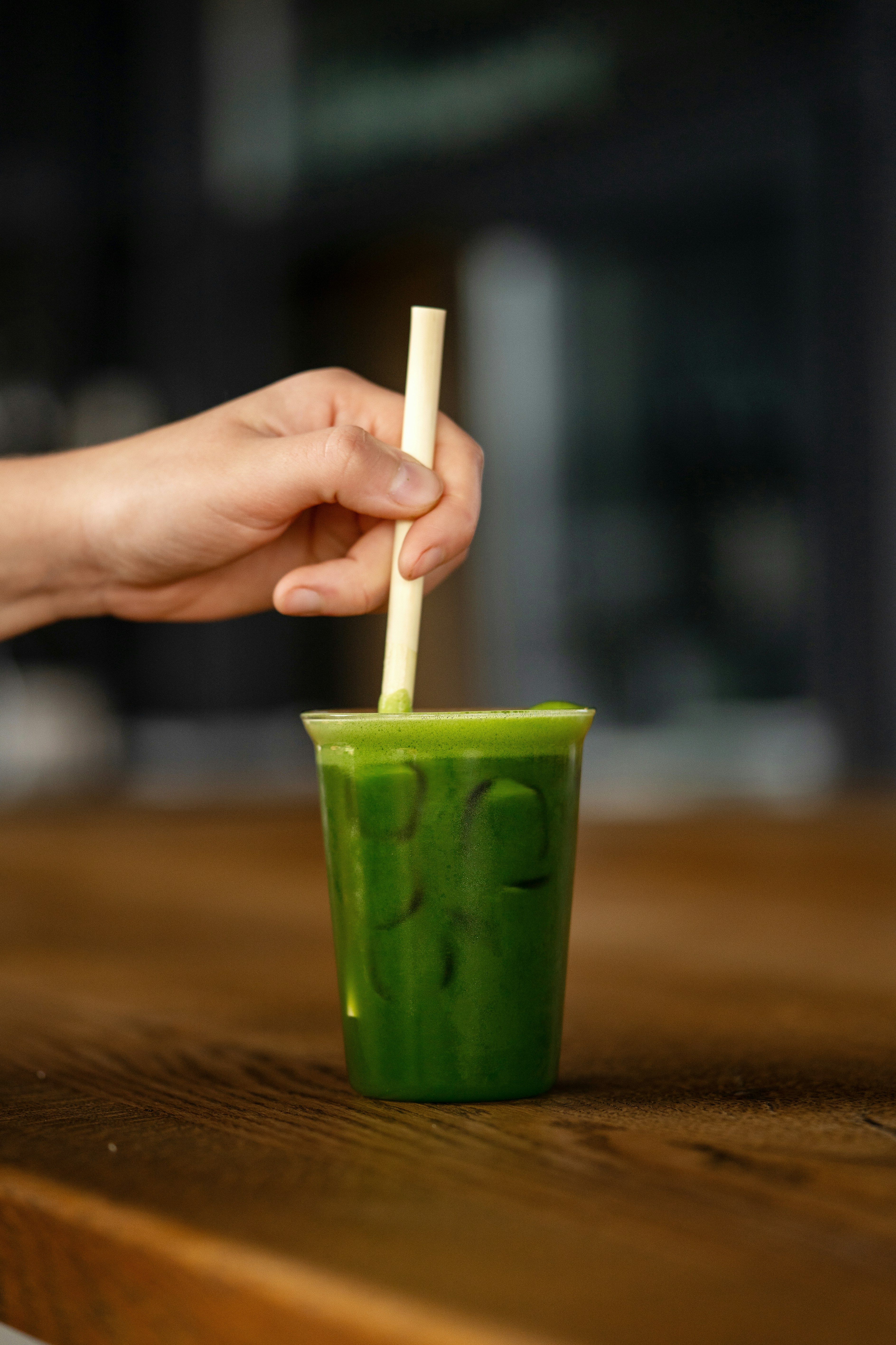 a person holding a straw in a green cup