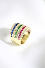 a gold ring with multicolored stones on it
