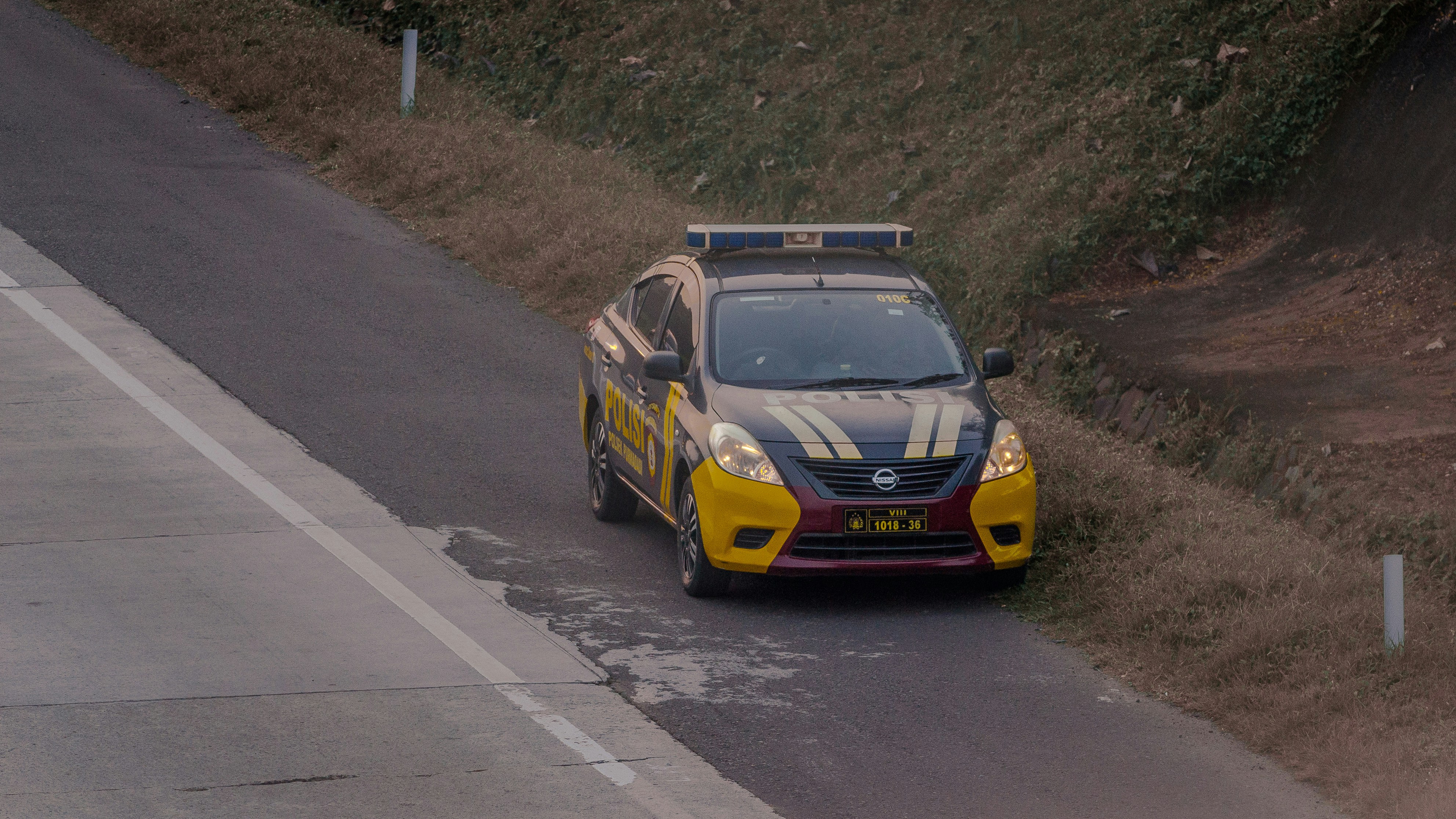 a yellow and black car driving down a road