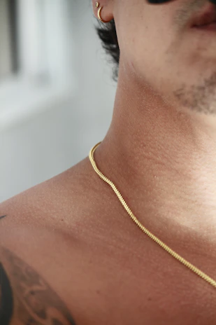a close up of a man wearing a gold necklace