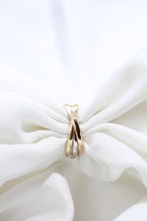 a pair of gold rings sitting on top of a white cloth