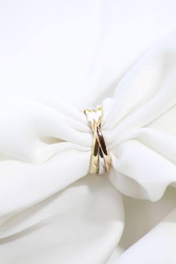 a close up of a white cloth with a gold ring on it