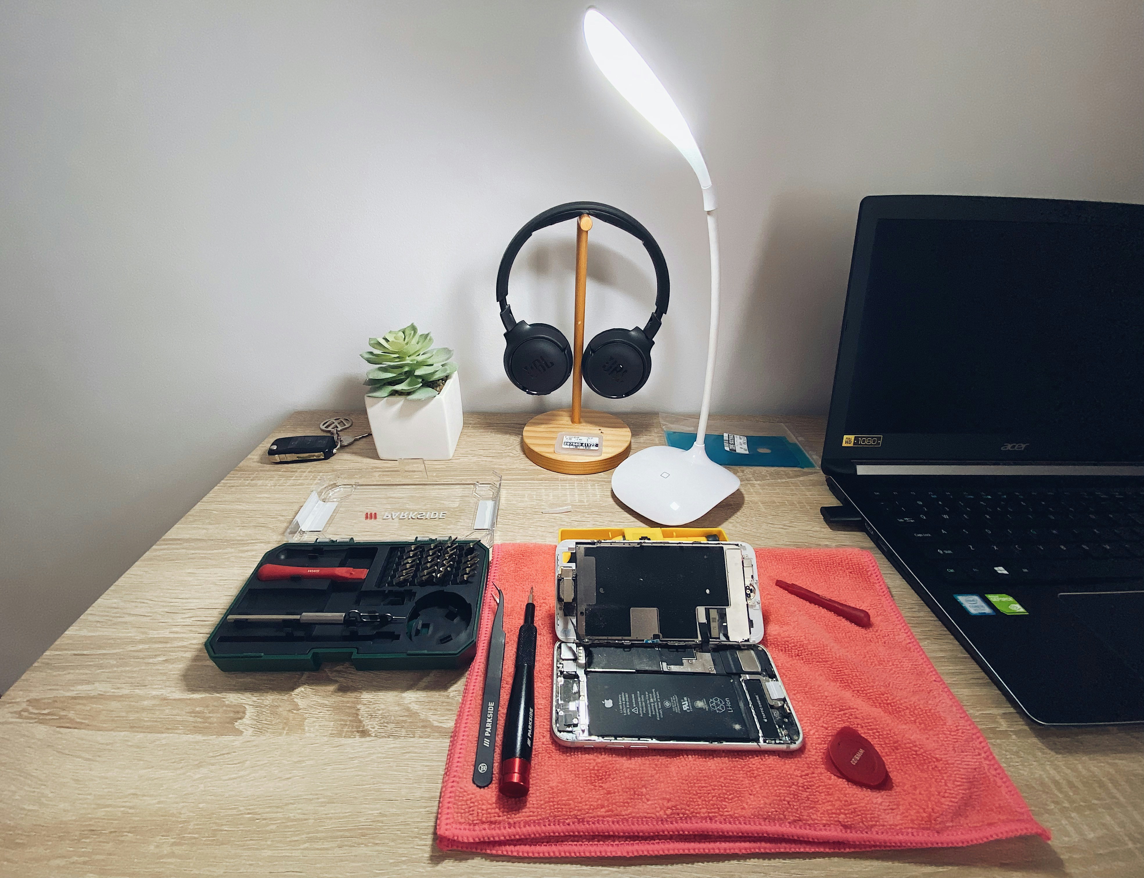 Bancada de assistência técnica com ferramentas e celular sendo reparado