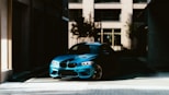 a blue car parked in front of a tall building