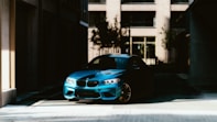 a blue car parked in front of a tall building