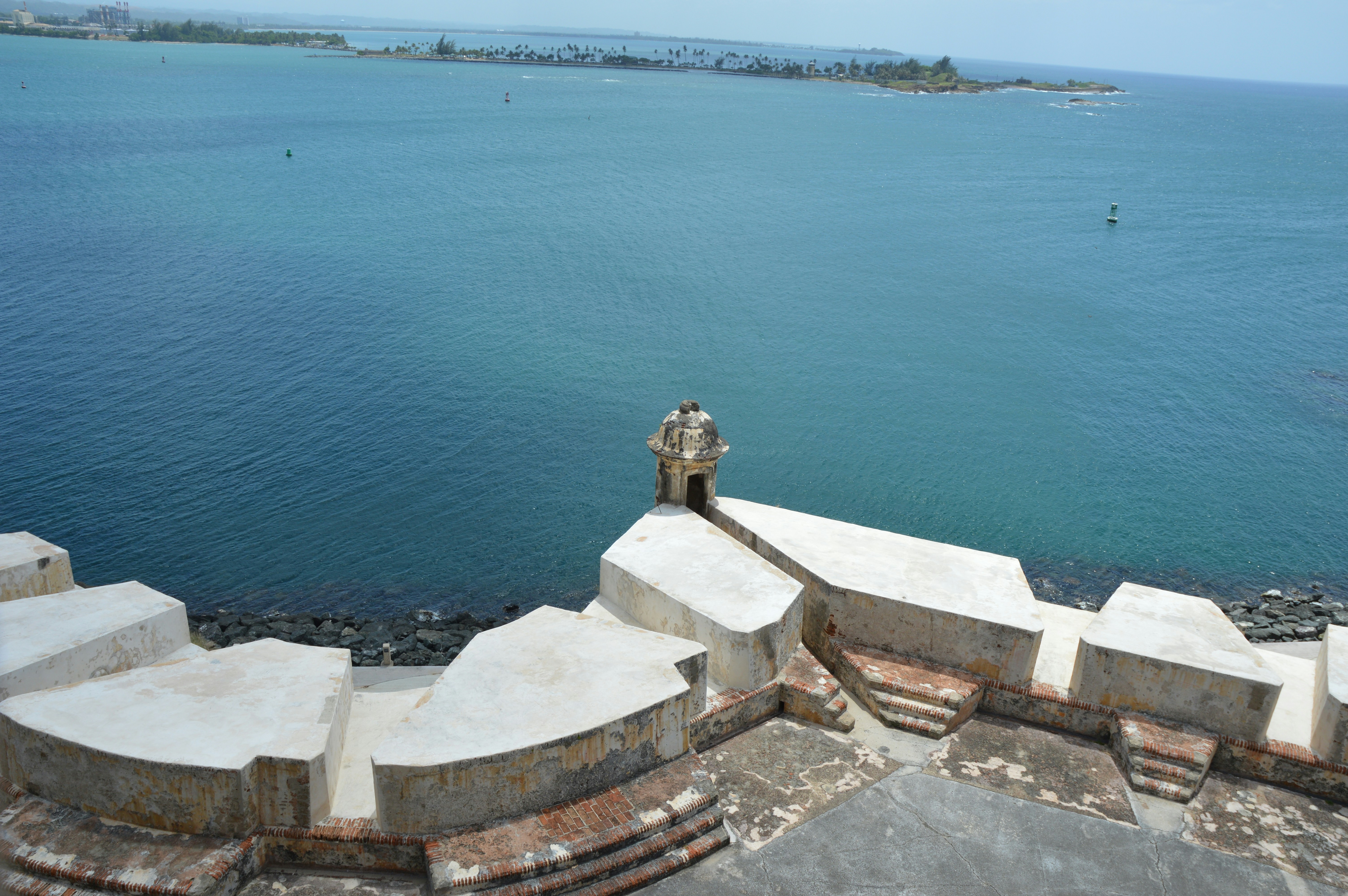 a man standing on top of a stone wall next to the ocean