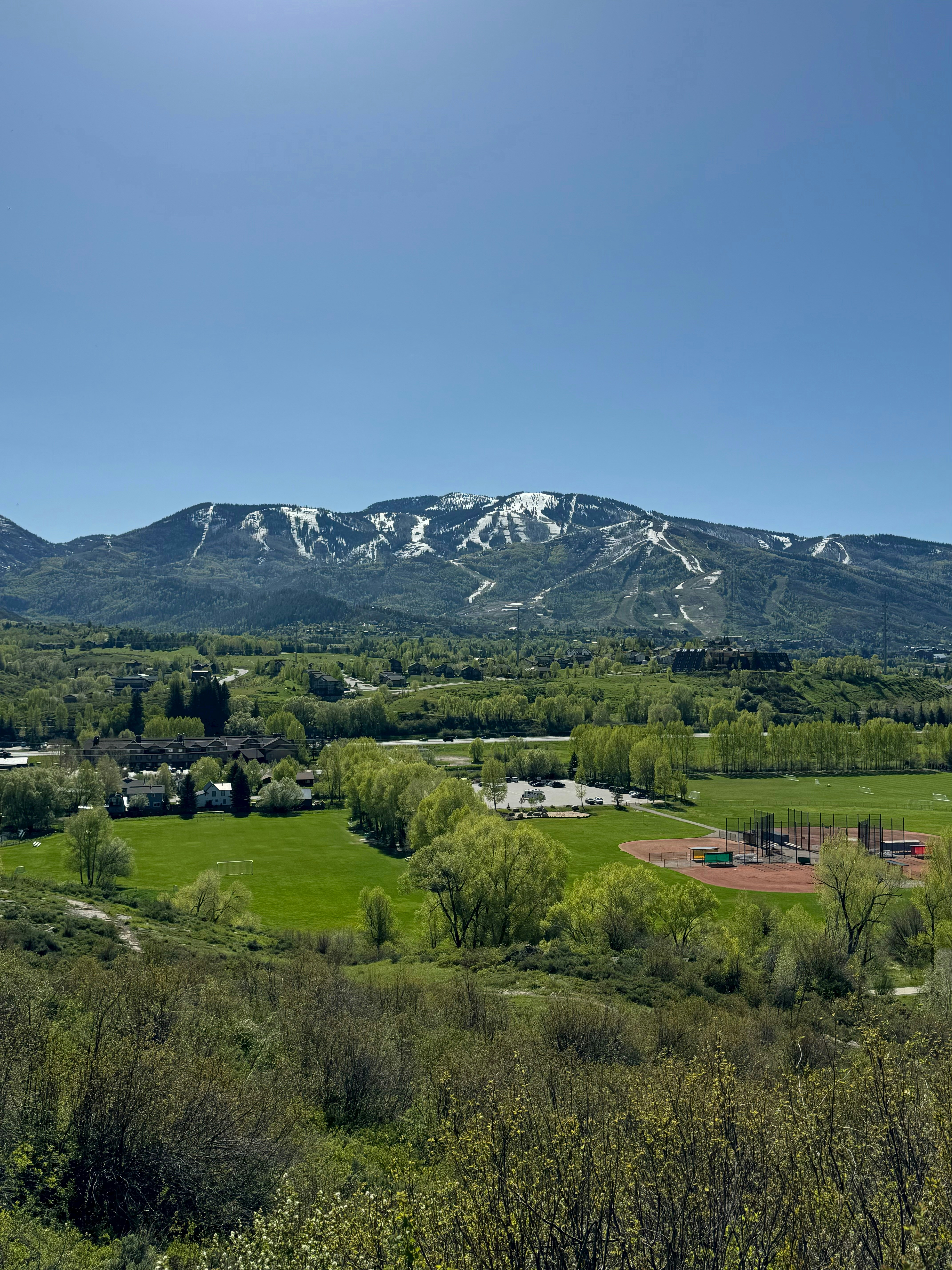 a view of a mountain range with a baseball field in the foreground