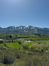 a view of a mountain range with a baseball field in the foreground
