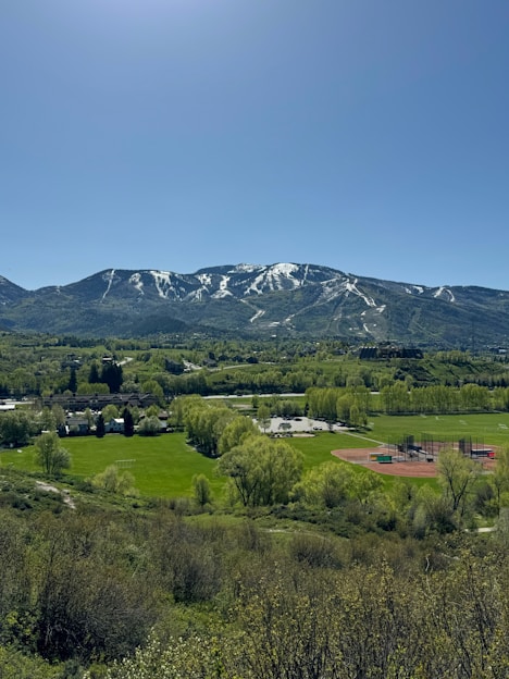 a view of a mountain range with a baseball field in the foreground