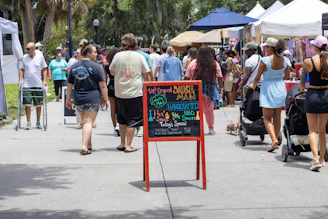 a group of people walking down a sidewalk next to a sign