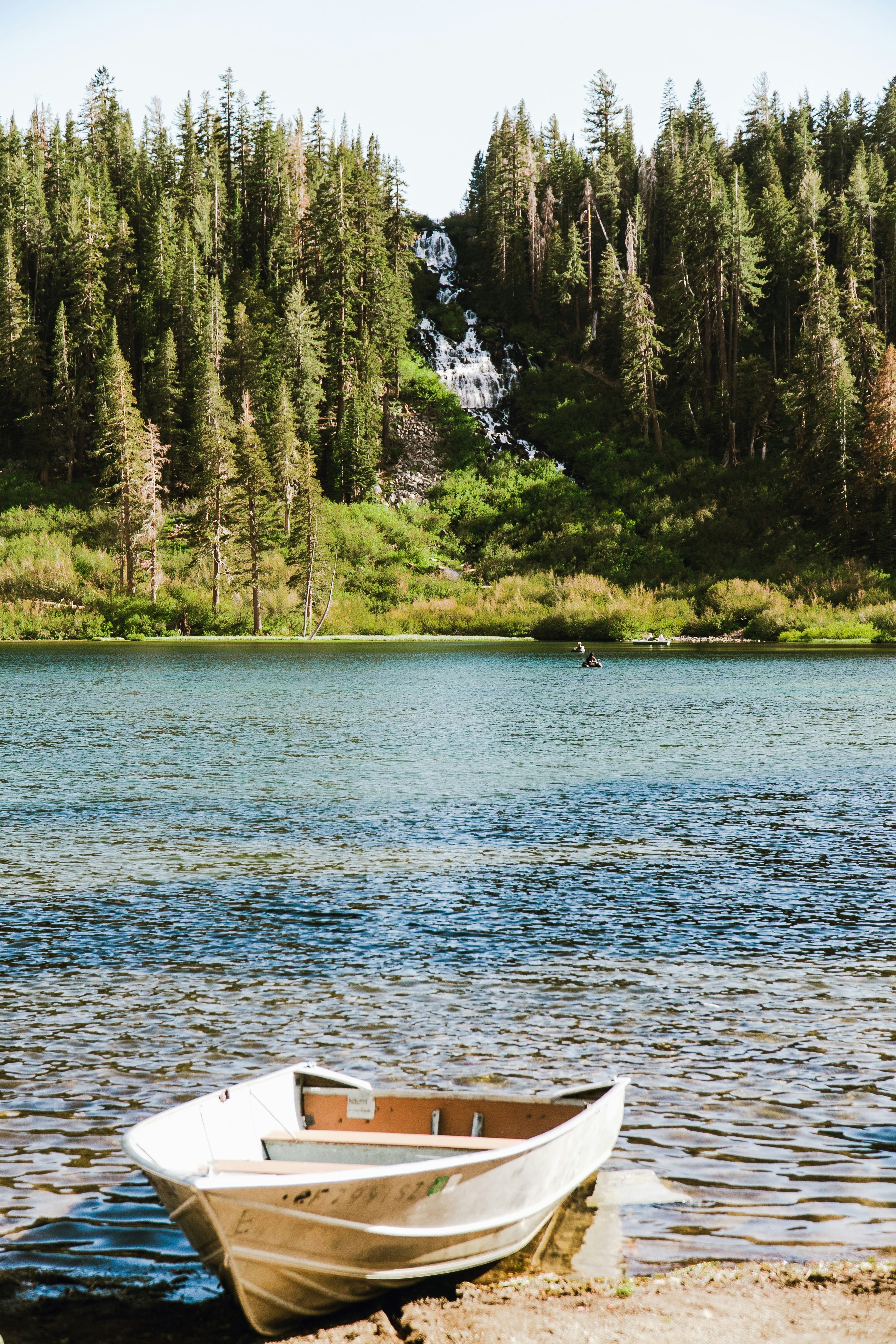 A small boat sitting on the shore of a lake photo – Free Summer Image ...