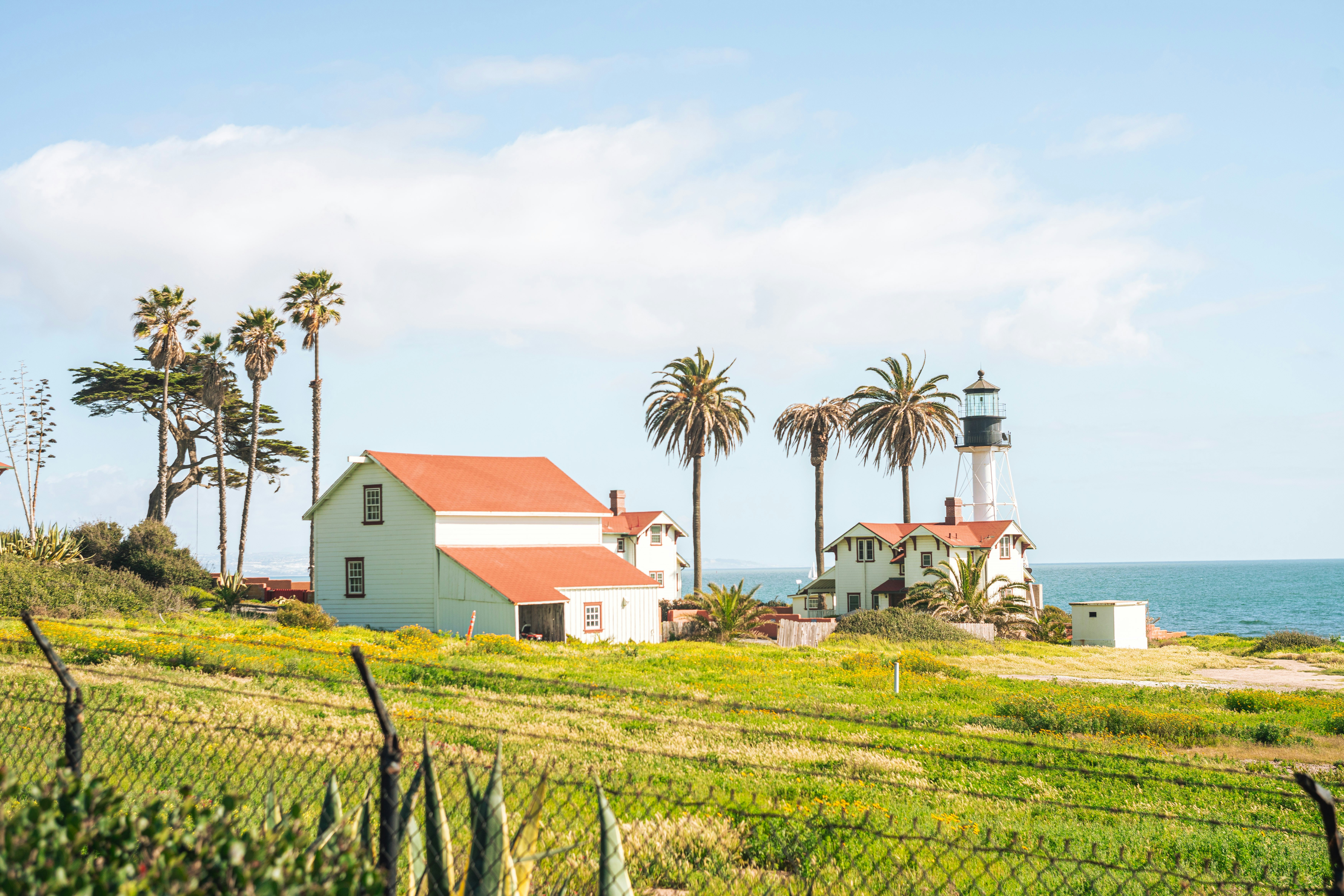 a white house with a red roof next to the ocean