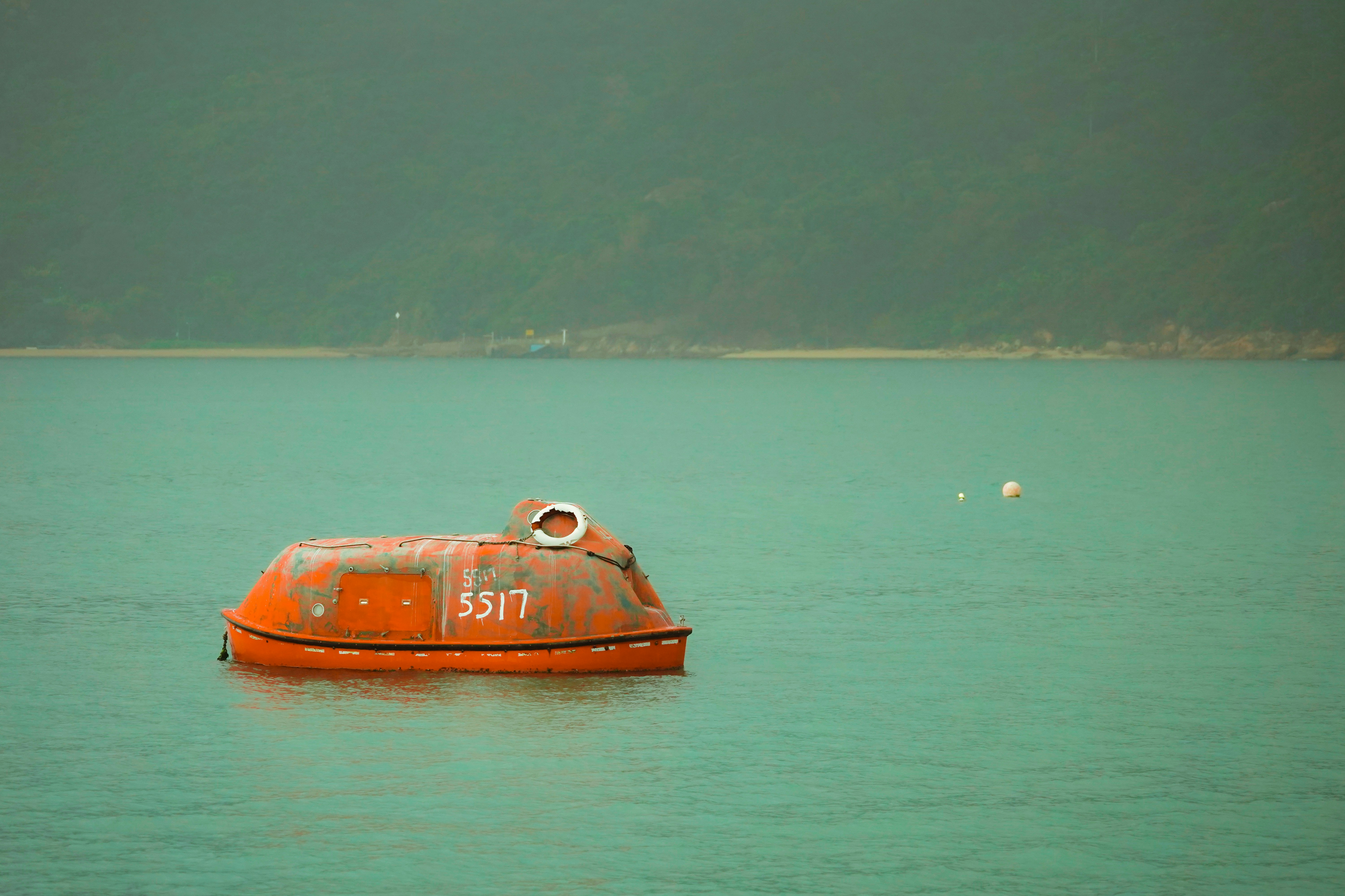 a small orange boat floating on top of a lake