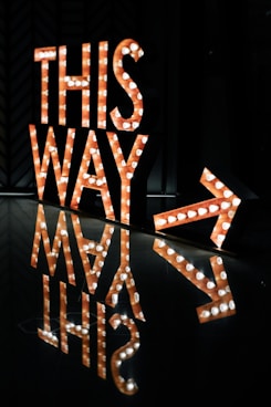 a lighted sign that says this way next to it