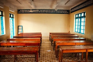 an empty classroom with wooden desks and windows