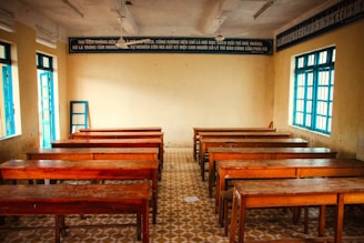 an empty classroom with wooden desks and windows