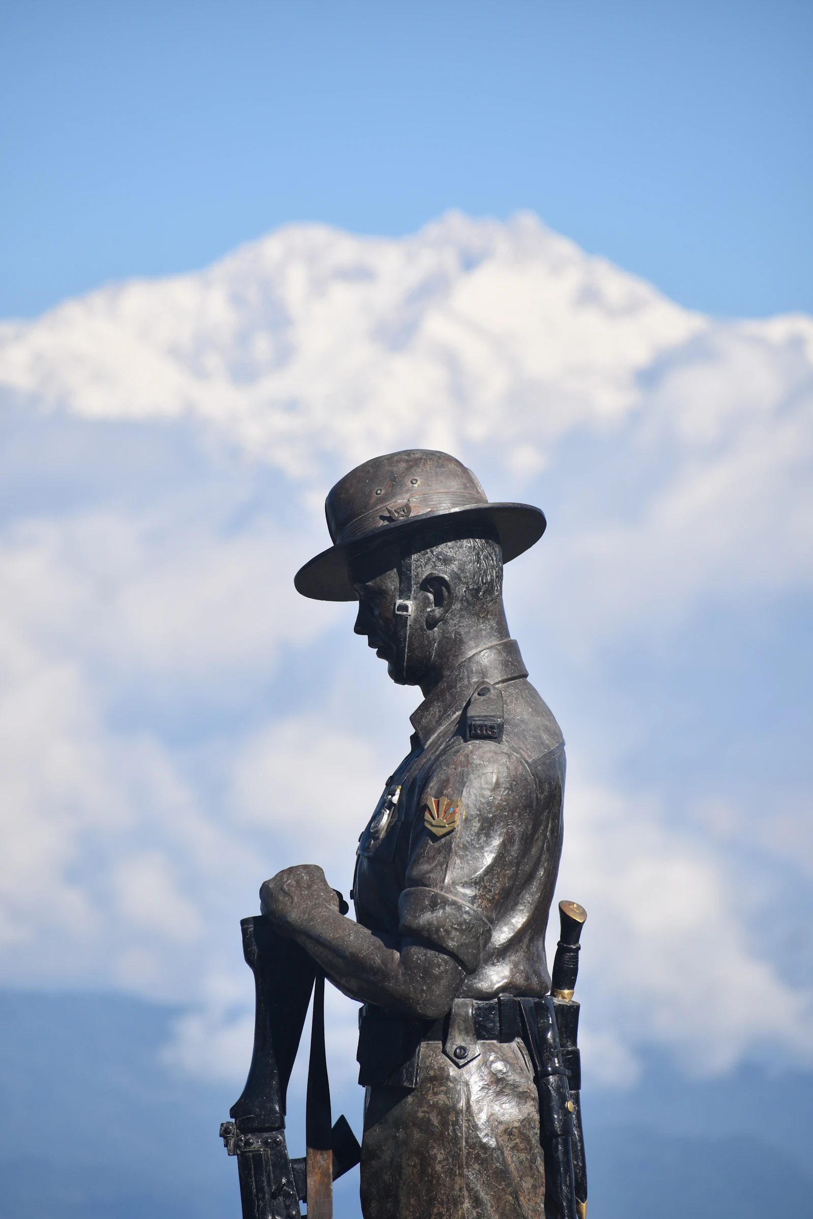 The bronze Gorkha soldier of the Batasia Loop war memorial with Kanchenjunga's snows behind