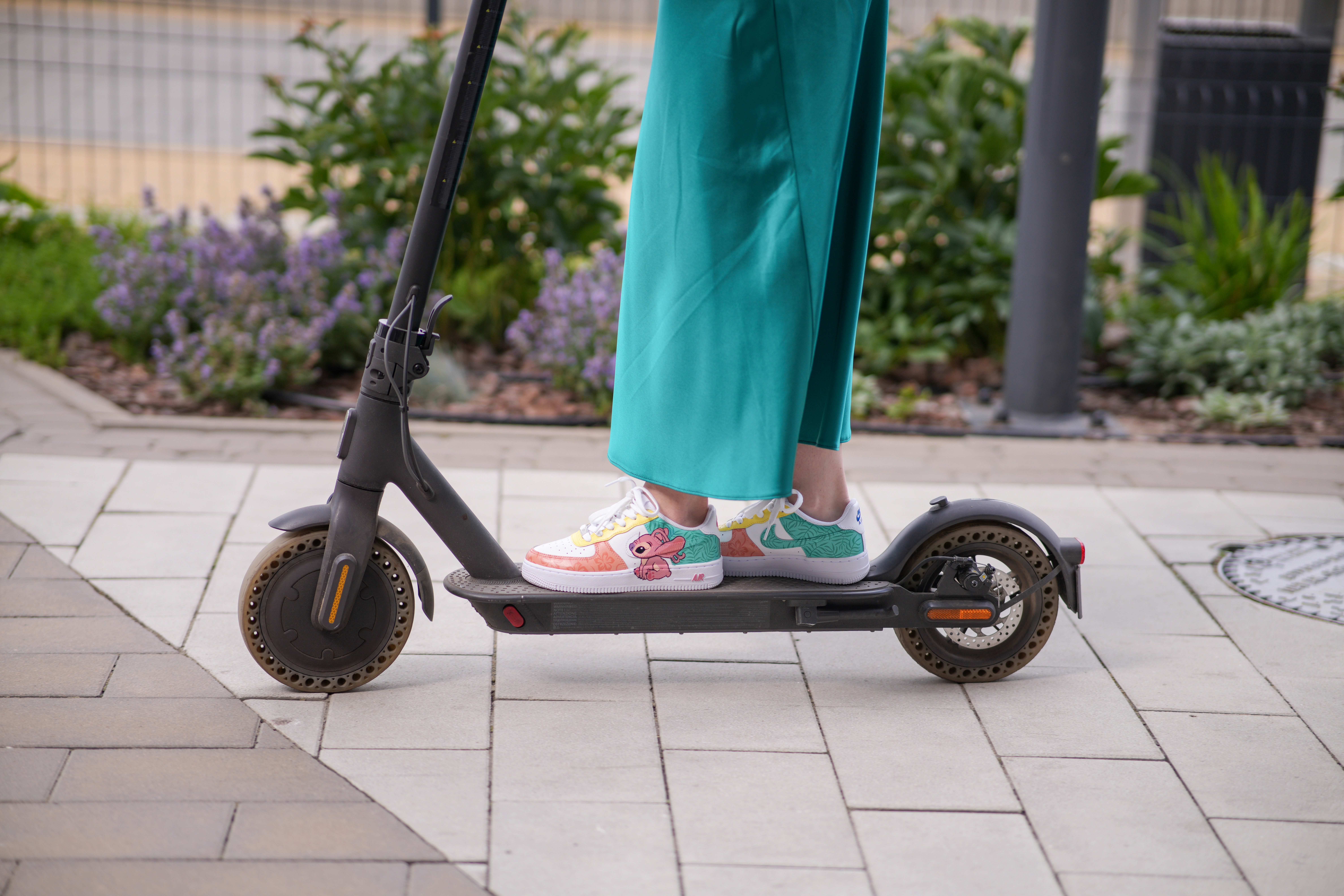 a person standing on a scooter on a sidewalk
