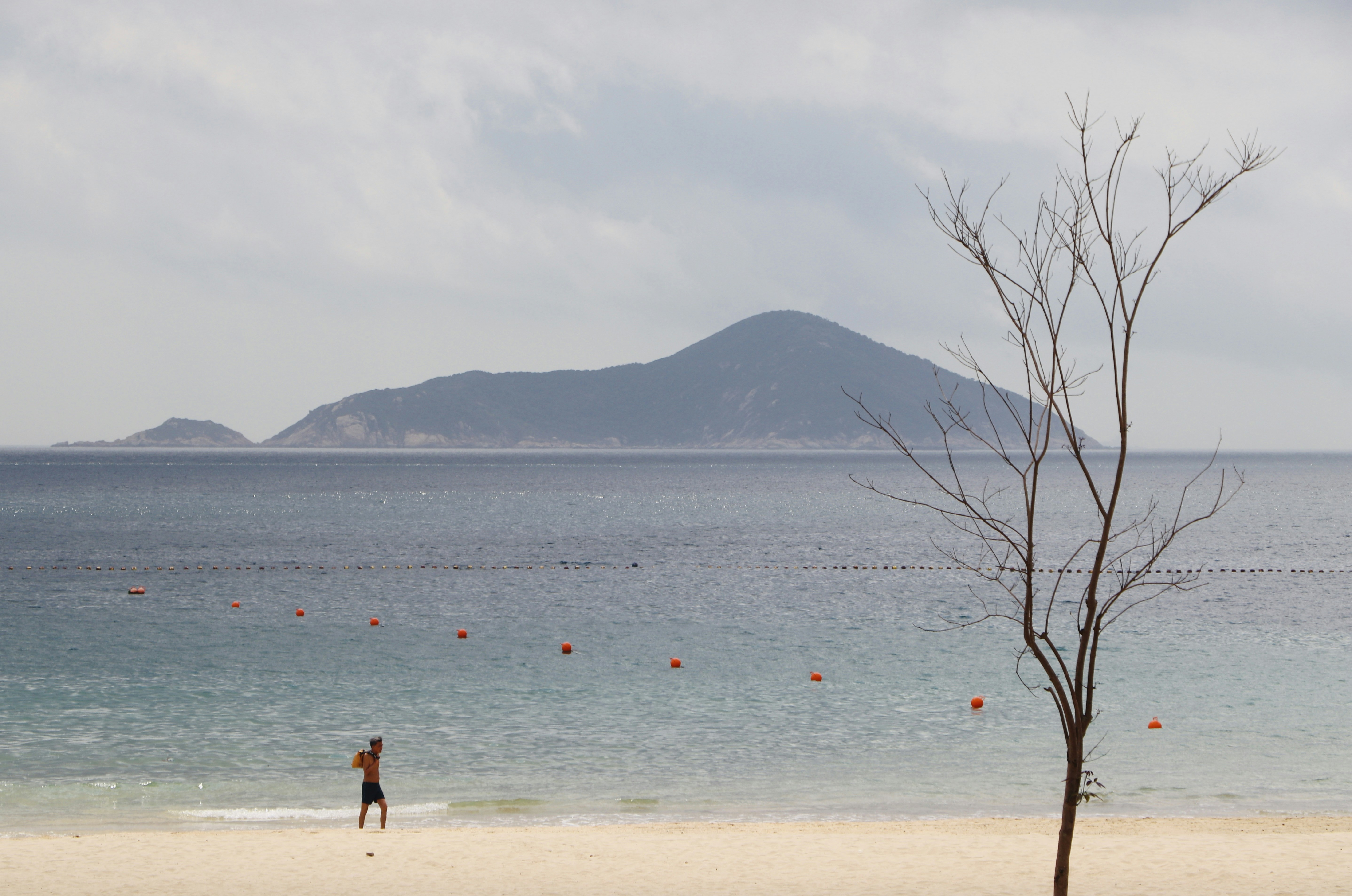 A man standing on top of a sandy beach next to the ocean photo – Free ...