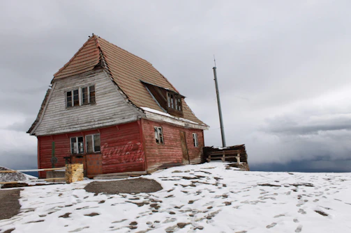 a red house sitting on top of a snow covered hill