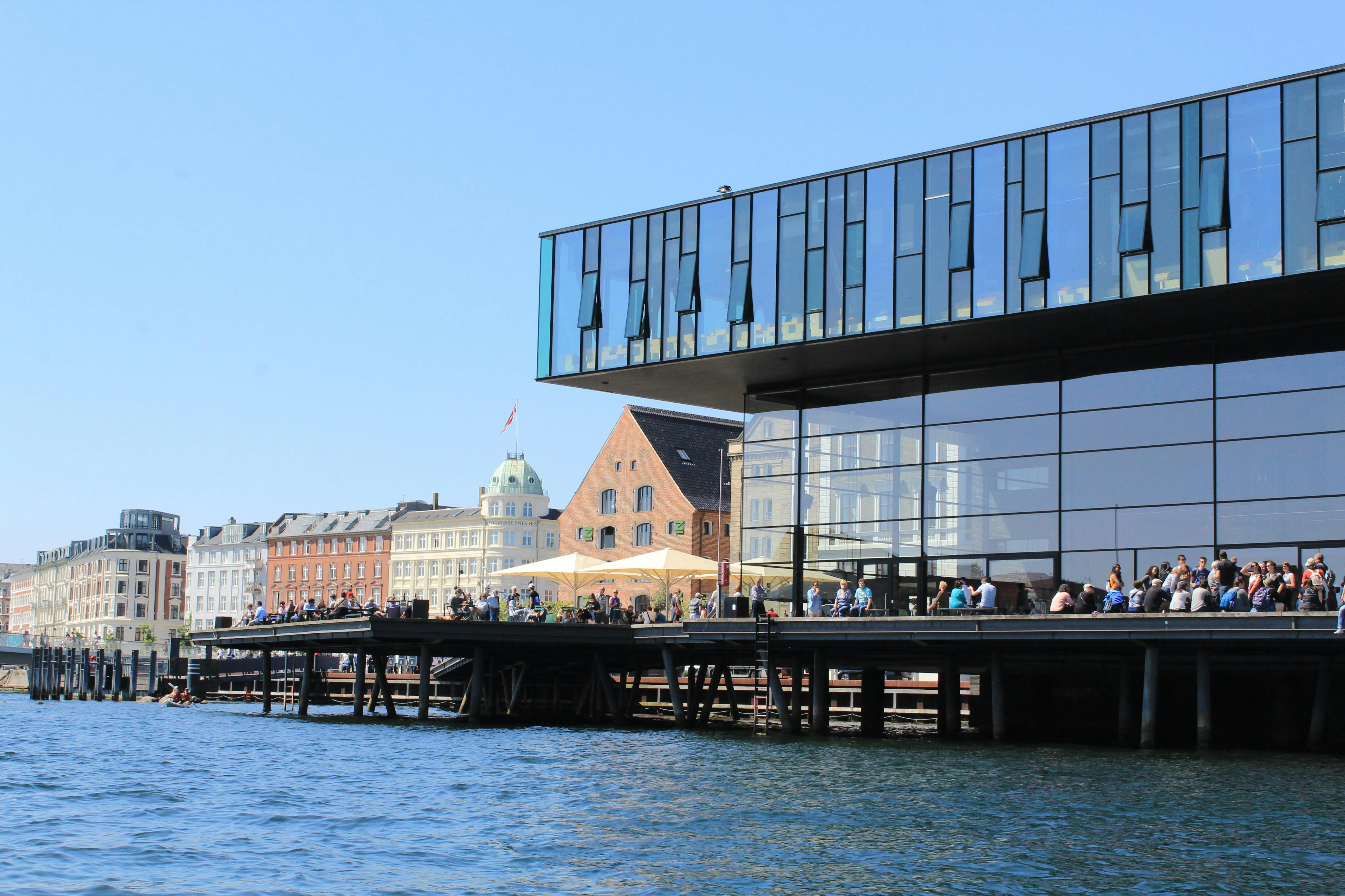 a group of people standing on a pier next to a body of water