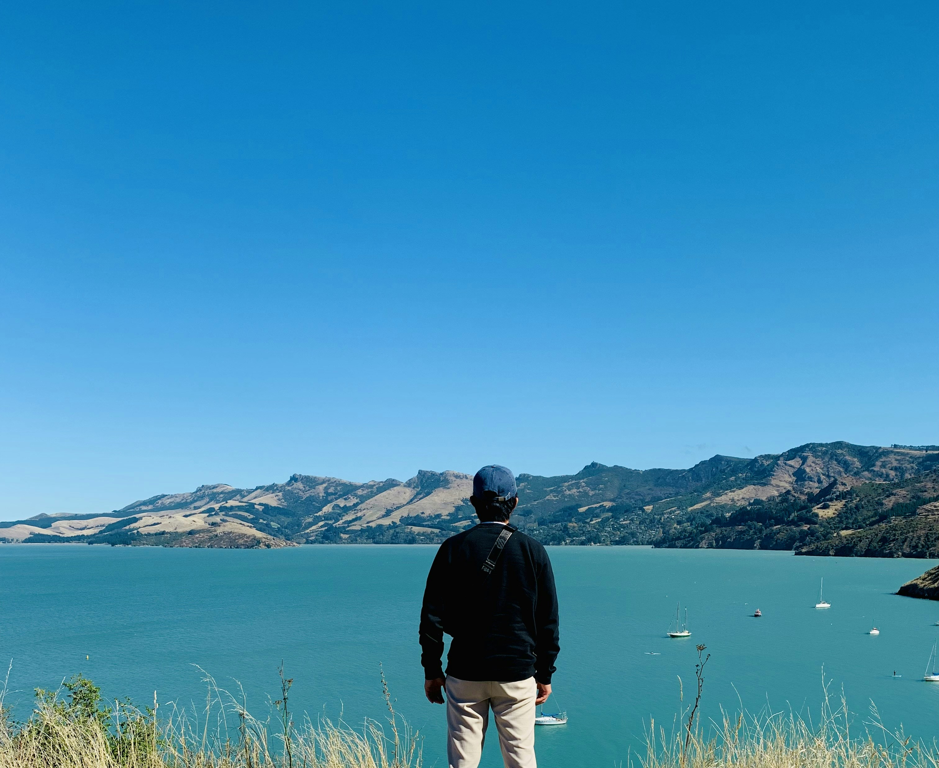 a man standing on top of a grass covered hillside