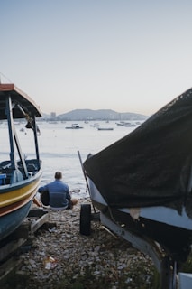 a man sitting on the ground next to a boat