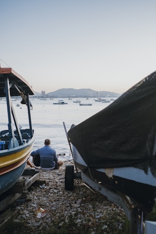 a man sitting on the ground next to a boat