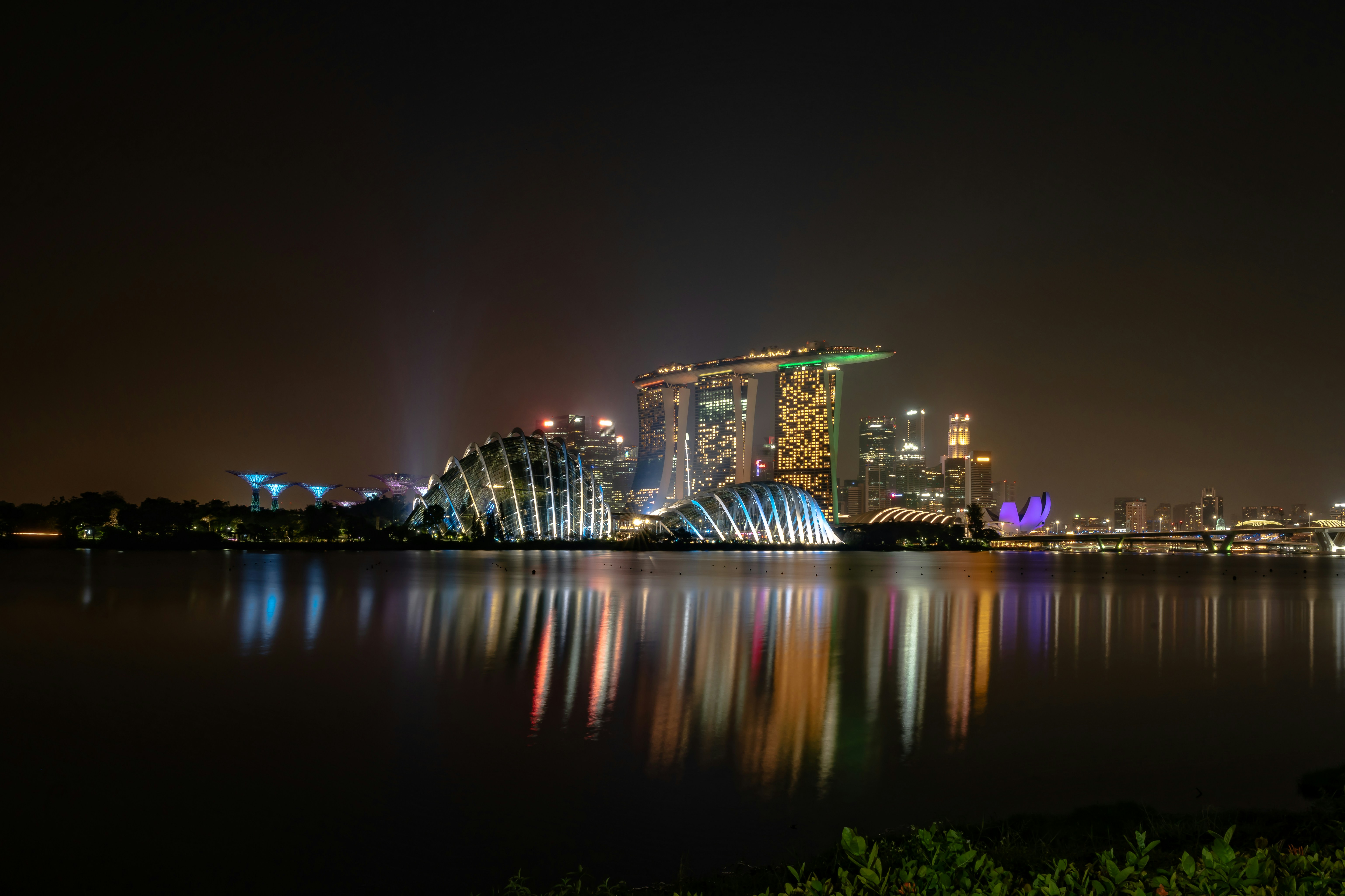 Modern Singapore financial district at night with glowing office towers, dark sky, deep shadows on glass facades