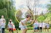 a young boy holding a yellow hula hoop in front of a group of people