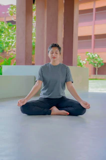 a man sitting in a lotus position in front of a building