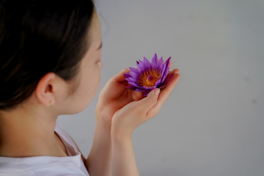 a woman holding a purple flower in her hands
