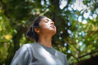 a woman standing in front of a tree with her eyes closed